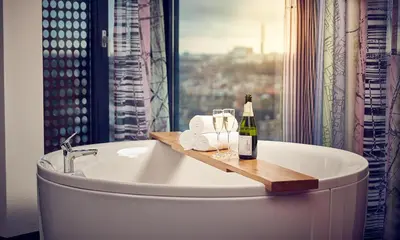 a bathroom with a bath tub with a bottle of wine at Inntel Hotels Utrecht Centre in Utrecht