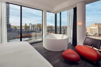 a bedroom with a bath tub and a large window at Inntel Hotels Utrecht Centre in Utrecht