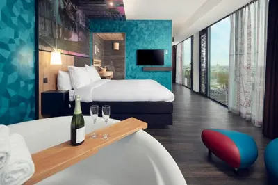 a hotel room with a bed and a tub with wine glasses at Inntel Hotels Utrecht Centre in Utrecht