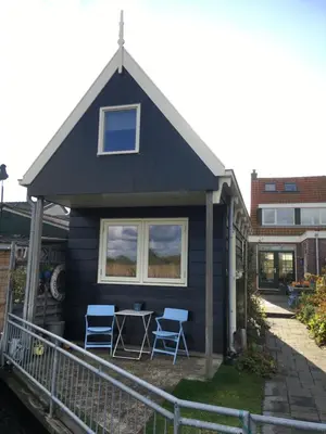 a blue house with two chairs and a table at Het Pulletje in Westzaan