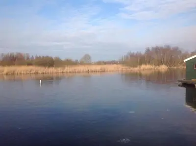 a view of a lake with a house on a dock at Het Pulletje in Westzaan