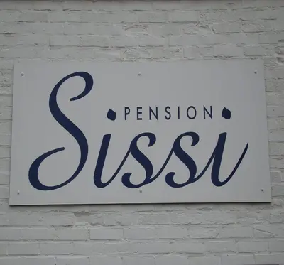 a sign on a white brick wall at Pension Sissi in Zandvoort