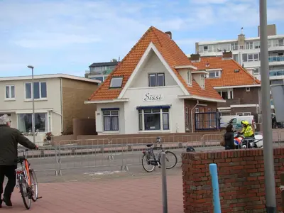a man riding a bike in front of a house at Pension Sissi in Zandvoort