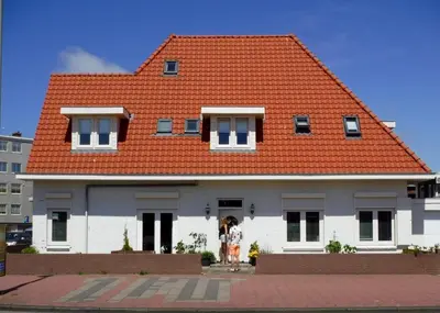 a house with an orange roof with people standing outside at Pension Sissi in Zandvoort