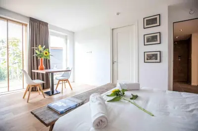 a white bedroom with a bed and a table with chairs at Amsterdam Area Residence Oosterwold in Almere