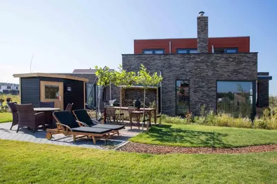 a house with chairs and tables in a yard at Amsterdam Area Residence Oosterwold in Almere