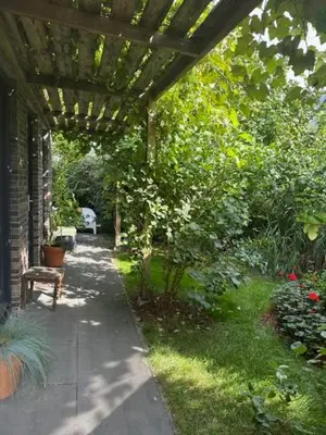 a garden with a pergola and a bench on a sidewalk at Amsterdam Area Residence Oosterwold in Almere