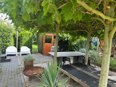 a patio with a table and chairs under a tree at Amsterdam Area Residence Oosterwold in Almere