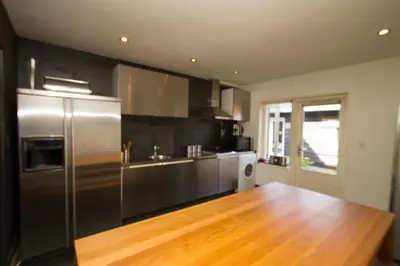 a kitchen with a stainless steel refrigerator and a wooden floor at Hannahhoeve Private House with wifi and free parking for 1 car in Weesp