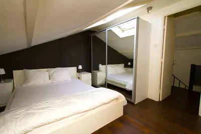 a bedroom with a large white bed and a mirror at Hannahhoeve Private House with wifi and free parking for 1 car in Weesp