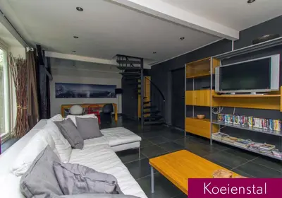 a living room with a white couch and a tv at Hannahhoeve Private House with wifi and free parking for 1 car in Weesp