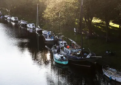 a group of boats are docked in a river at SWEETS - Gerben Wagenaarbrug in Amsterdam