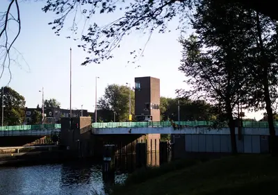 a bridge over a river with a building in the background at SWEETS - Gerben Wagenaarbrug in Amsterdam