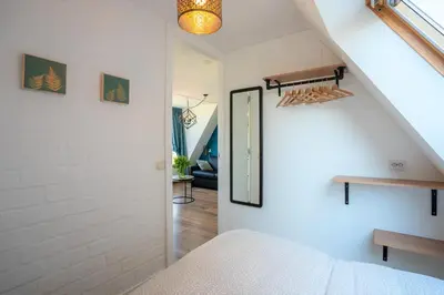 a room with a bed and a mirror and a staircase at CasaMare in Egmond aan Zee