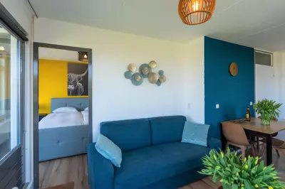 a living room with a blue couch and a bed at CasaMare in Egmond aan Zee