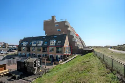 a building on top of a hill next to a field at CasaMare in Egmond aan Zee