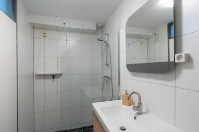 a white bathroom with a shower and a sink at CasaMare in Egmond aan Zee