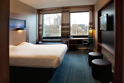 a hotel room with a bed and a desk and a window at Skotel Amsterdam, Hotelschool The Hague in Amsterdam