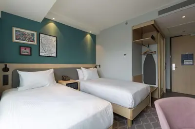 a hotel room with two beds and a chair at Hampton By Hilton Utrecht Centraal Station in Utrecht