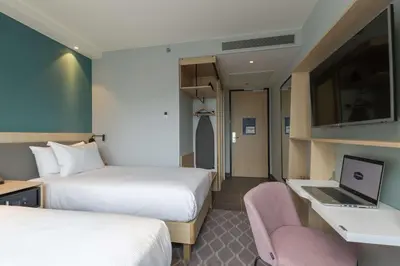 a hotel room with two beds and a laptop on a desk at Hampton By Hilton Utrecht Centraal Station in Utrecht