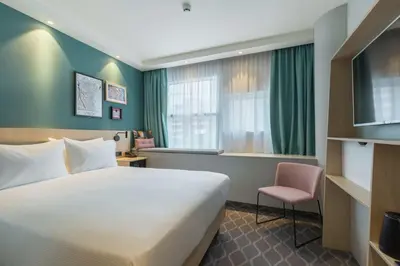 a hotel room with a bed and a chair at Hampton By Hilton Utrecht Centraal Station in Utrecht
