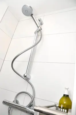 a shower head in a bathroom with a yellow bottle at Beachhouse Bosweg in Noordwijk aan Zee
