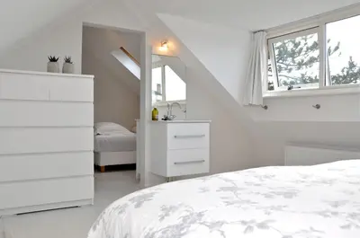 a white bedroom with a bed and a mirror at Beachhouse Bosweg in Noordwijk aan Zee