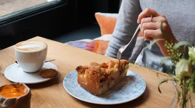 a person eating a piece of cake and a cup of coffee at Hotel 't Fnidsen in Alkmaar