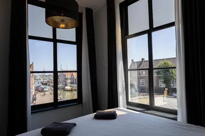 a bedroom with two pillows on a bed and two windows at Hotel en Stadscafé de Dam l Hotel Monnickendam in Monnickendam