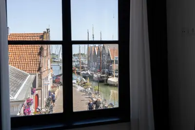 a window with a view of a canal with boats at Hotel en Stadscafé de Dam l Hotel Monnickendam in Monnickendam