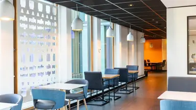 a row of tables and chairs in a room with windows at Holiday Inn Express Utrecht - Papendorp by IHG in Utrecht