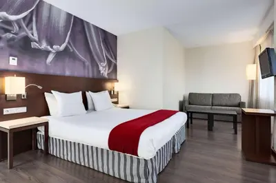 a hotel room with a large bed and a chair at NH Amersfoort in Amersfoort