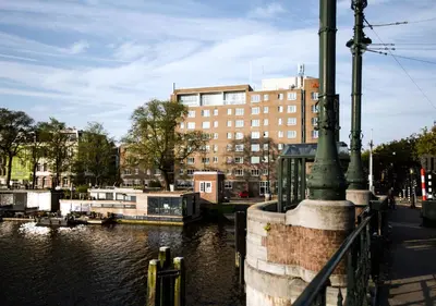 a river with a building in the background at SWEETS - Nieuwe Amstelbrug in Amsterdam