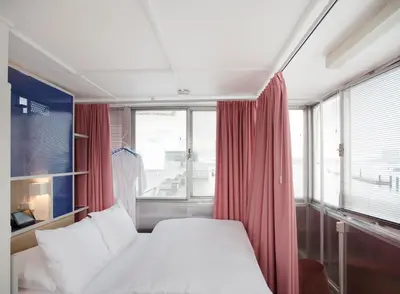 a bedroom with a bed and a window with red curtains at SWEETS - Westerdoksbrug in Amsterdam
