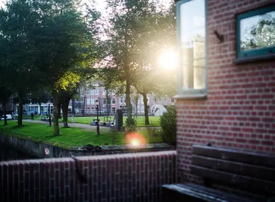 a brick building with a bench in a park at SWEETS - Kattenslootbrug in Amsterdam