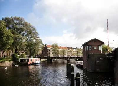 a river with a bridge and boats on it at SWEETS - Kattenslootbrug in Amsterdam