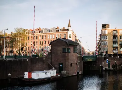 a boat in the water next to a brick building at SWEETS - Kattenslootbrug in Amsterdam