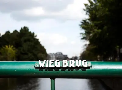 a sign on a green railing with the word vaccinebush at SWEETS - Wiegbrug in Amsterdam