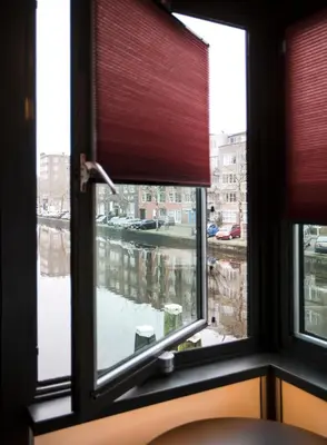 a window with a view of a river seen through it at SWEETS - Theophile de Bockbrug in Amsterdam