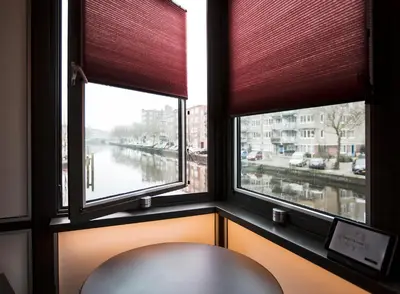 a window with a chair in a room with a view at SWEETS - Theophile de Bockbrug in Amsterdam