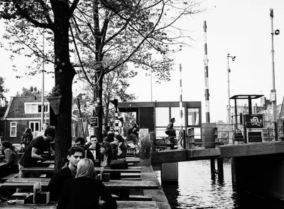 a group of people sitting at tables by the water at SWEETS - Theophile de Bockbrug in Amsterdam
