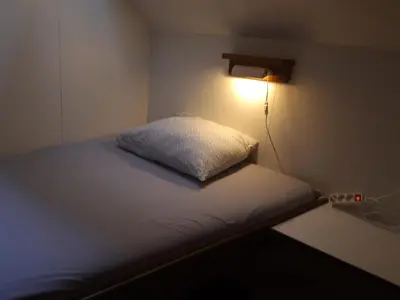 a bed in a room with a light on the wall at Felicitas in Amsterdam