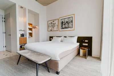 a bedroom with a large white bed and a stool at Hotel Pontsteiger in Amsterdam