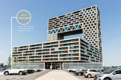 a tall building with cars parked in a parking lot at Hotel Pontsteiger in Amsterdam