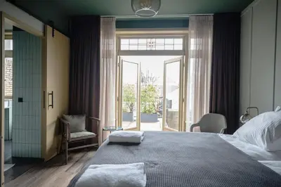 a bedroom with a large bed and a large window at Seabreeze Suites - near Zandvoort aan Zee in Overveen