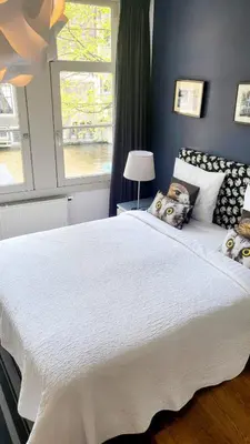 a large white bed in a room with a window at Velvetamsterdam in Amsterdam