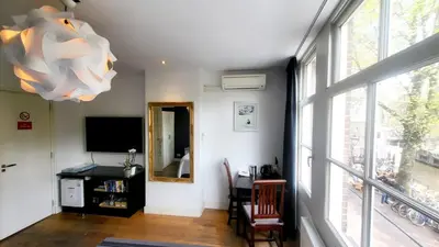 a living room with a table and a large window at Velvetamsterdam in Amsterdam