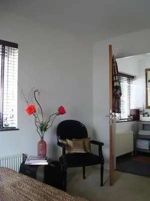 a bedroom with a chair and a vase with flowers at B&B Habitat in Beverwijk