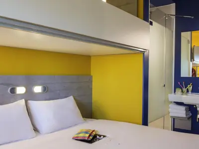 a bedroom with a white bed with a yellow wall at ibis budget Amsterdam Airport in Badhoevedorp