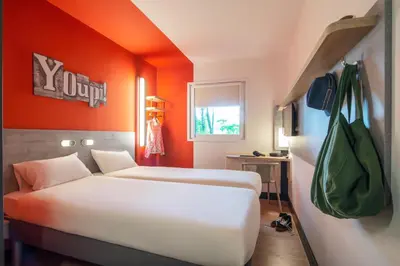 two beds in a room with an orange wall at ibis budget Amsterdam Airport in Badhoevedorp